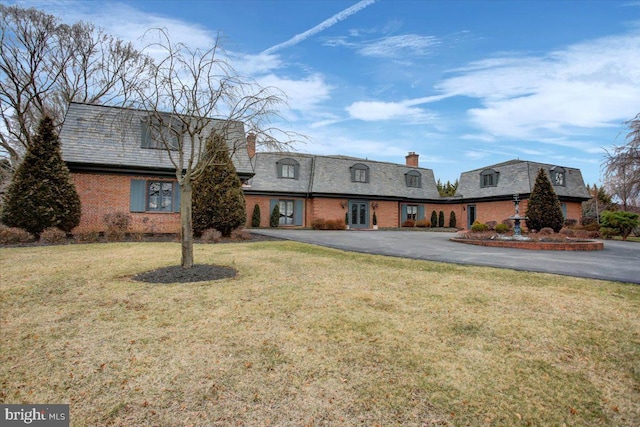 front of property with a chimney, a front lawn, aphalt driveway, and brick siding