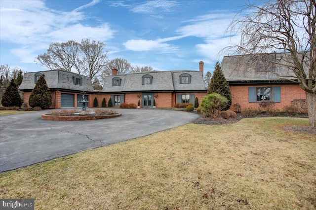 view of front of home featuring a garage, driveway, brick siding, and a chimney