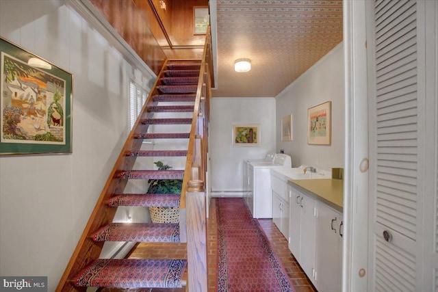 staircase featuring brick floor, washing machine and dryer, and crown molding