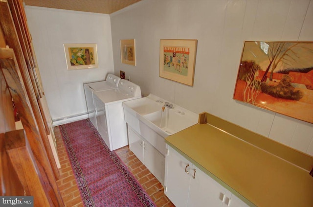 washroom featuring brick floor, washer and dryer, and cabinet space