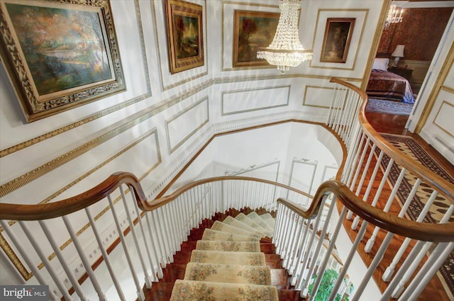 stairway featuring wallpapered walls and an inviting chandelier