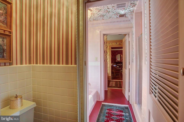 full bathroom with a bath, wallpapered walls, tile walls, and wainscoting