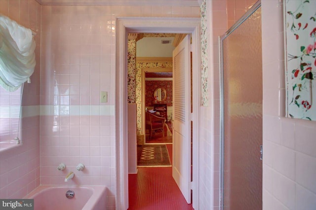 full bathroom featuring a washtub, tile patterned flooring, tile walls, and an enclosed shower