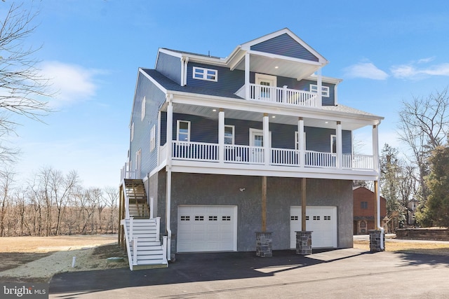 raised beach house with a porch, an attached garage, driveway, stairway, and stucco siding