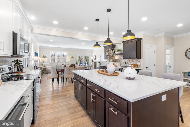 kitchen featuring open floor plan, appliances with stainless steel finishes, light wood-type flooring, and white cabinets