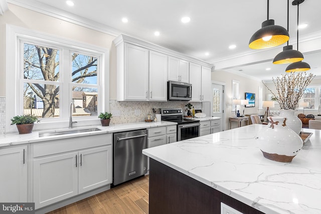 kitchen with crown molding, appliances with stainless steel finishes, a sink, and decorative backsplash