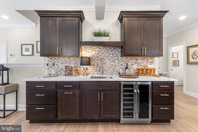 kitchen featuring dark brown cabinets, wine cooler, a sink, and crown molding