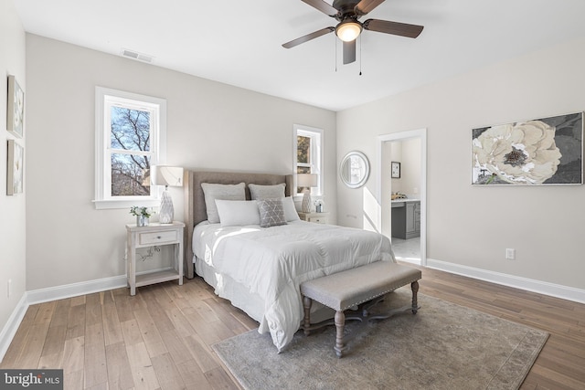 bedroom with light wood finished floors, baseboards, visible vents, and ensuite bathroom