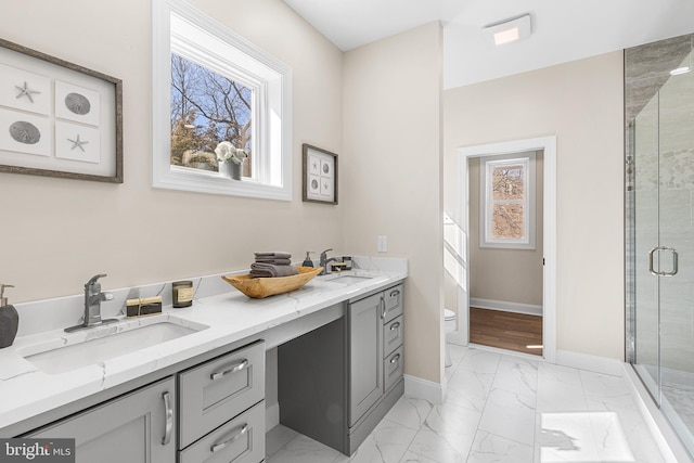 full bath featuring marble finish floor, a healthy amount of sunlight, a sink, and a shower stall