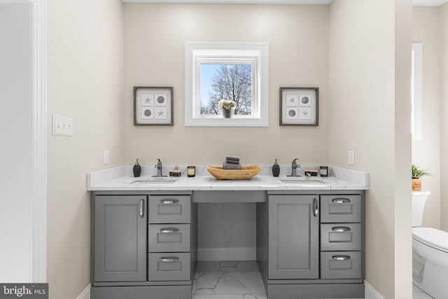 bathroom featuring marble finish floor, baseboards, a sink, and toilet