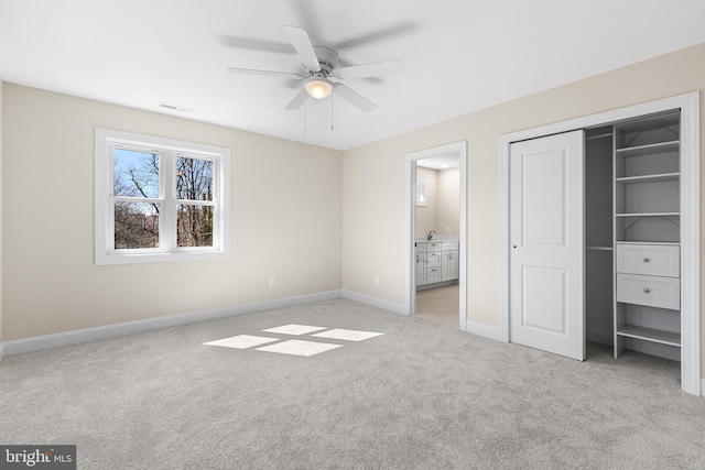 unfurnished bedroom with a closet, visible vents, ensuite bathroom, light carpet, and baseboards