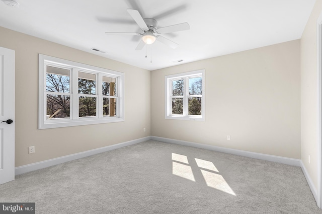 carpeted empty room featuring ceiling fan, visible vents, and baseboards