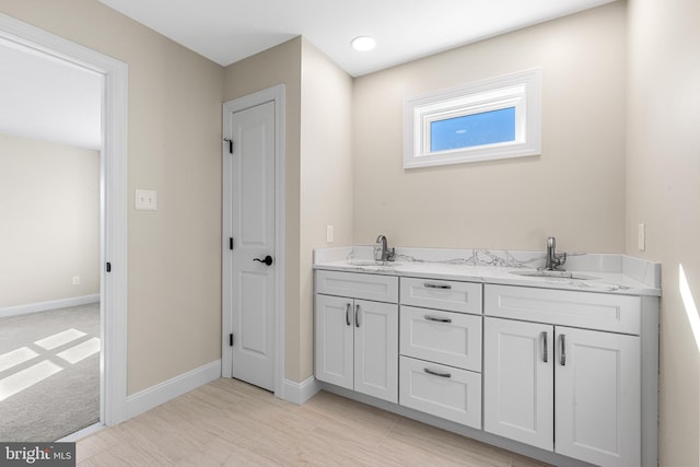 full bathroom featuring a sink, baseboards, and double vanity