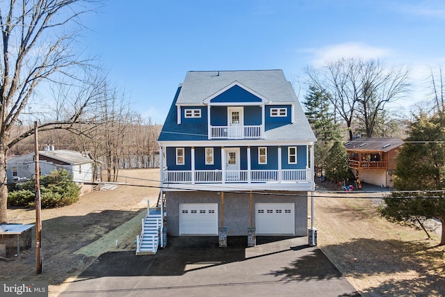 view of front of property with driveway, a garage, a balcony, stairway, and a porch