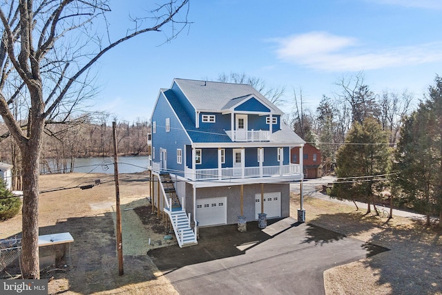 view of front facade featuring an attached garage, a balcony, a water view, driveway, and stairway