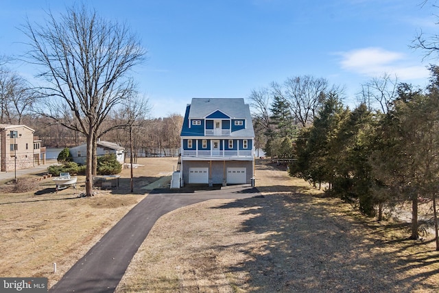 view of front facade with a garage, fence, and aphalt driveway