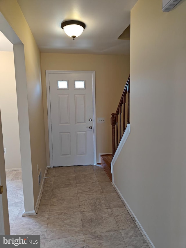 foyer with stairway, visible vents, and baseboards