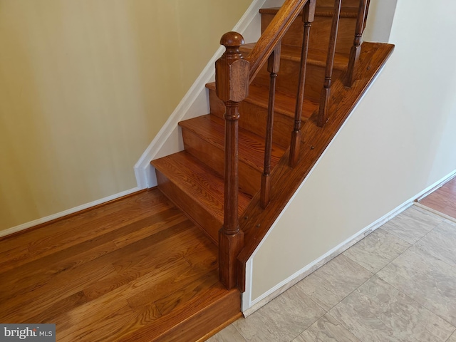 staircase featuring baseboards and wood finished floors