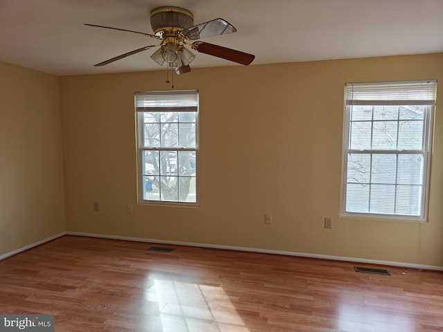 empty room with a healthy amount of sunlight, visible vents, and wood finished floors