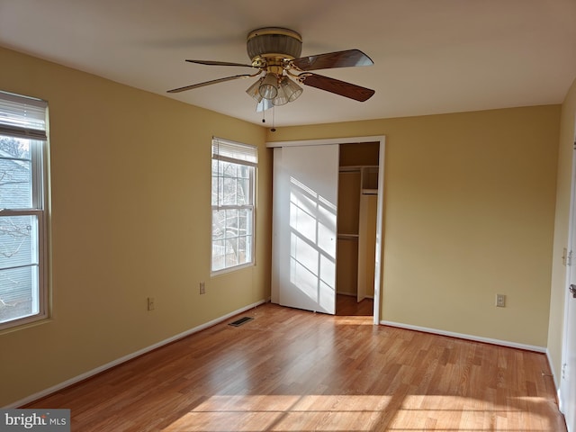 unfurnished bedroom featuring light wood finished floors, baseboards, visible vents, ceiling fan, and a closet