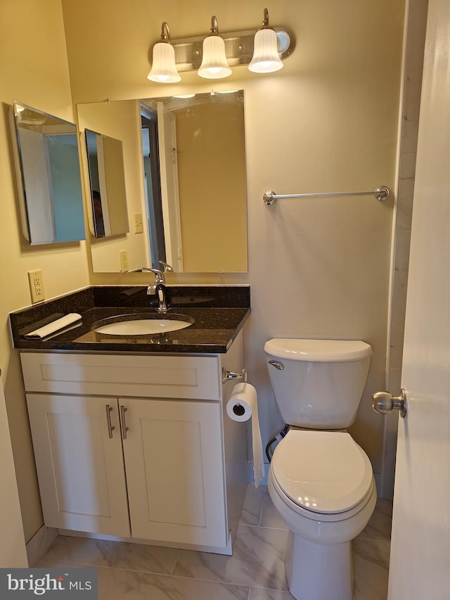 bathroom with marble finish floor, vanity, and toilet