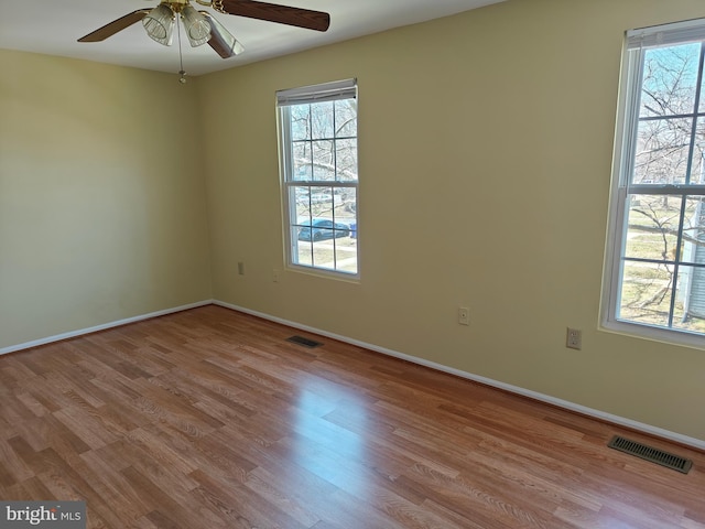 unfurnished room featuring visible vents, a wealth of natural light, and wood finished floors