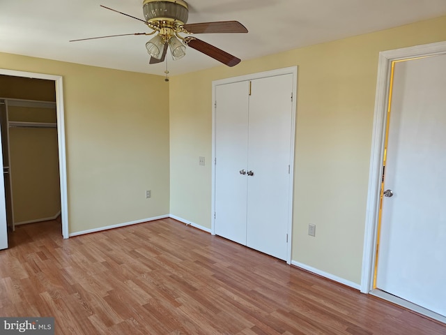 unfurnished bedroom featuring multiple closets, baseboards, and light wood finished floors