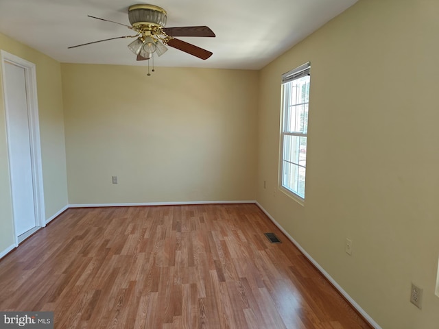 spare room with baseboards, ceiling fan, visible vents, and light wood-style floors