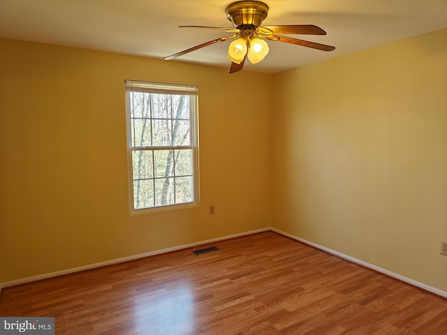 spare room featuring visible vents, baseboards, and wood finished floors