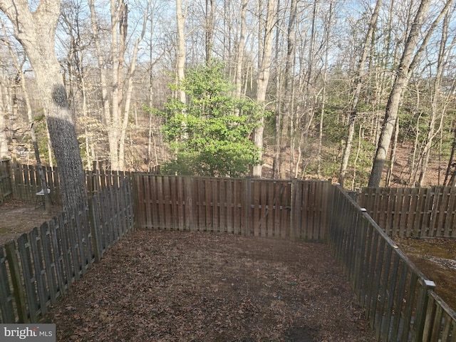 view of yard featuring a wooded view and a fenced backyard