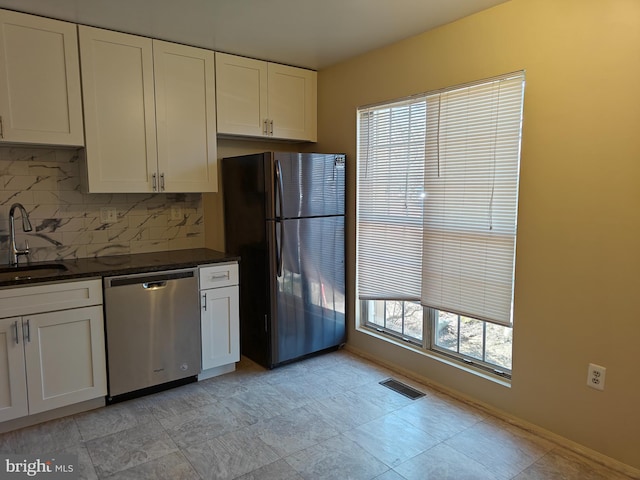 kitchen with visible vents, white cabinets, freestanding refrigerator, stainless steel dishwasher, and a sink