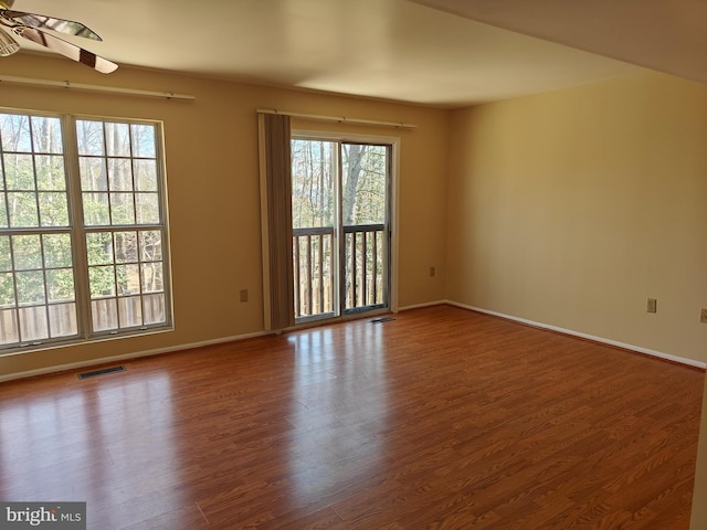 unfurnished room with visible vents, ceiling fan, baseboards, and wood finished floors