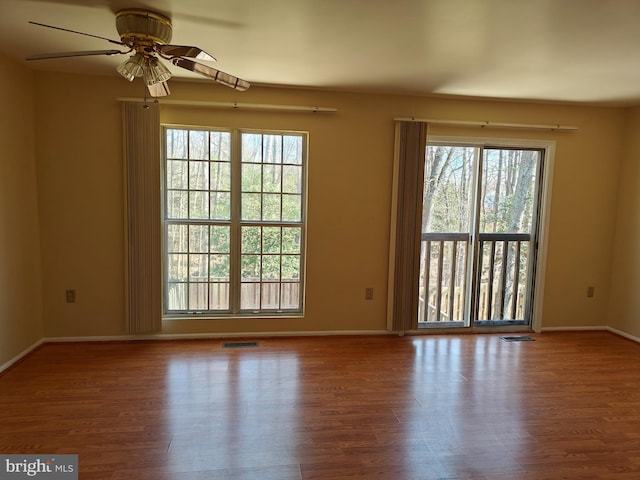 empty room featuring plenty of natural light, wood finished floors, and visible vents