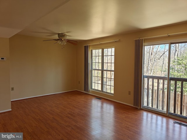 unfurnished room featuring baseboards, visible vents, and wood finished floors