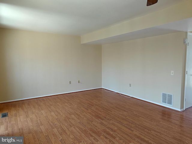 spare room featuring baseboards, visible vents, and wood finished floors