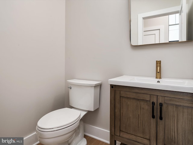 bathroom with toilet, baseboards, and vanity