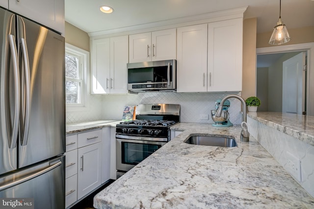 kitchen with light stone countertops, a sink, white cabinets, appliances with stainless steel finishes, and tasteful backsplash