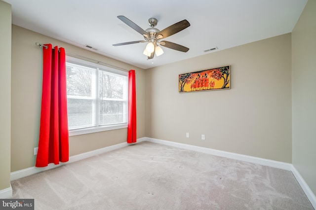 carpeted empty room with a ceiling fan, visible vents, and baseboards