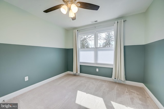 carpeted empty room featuring visible vents, baseboards, and ceiling fan