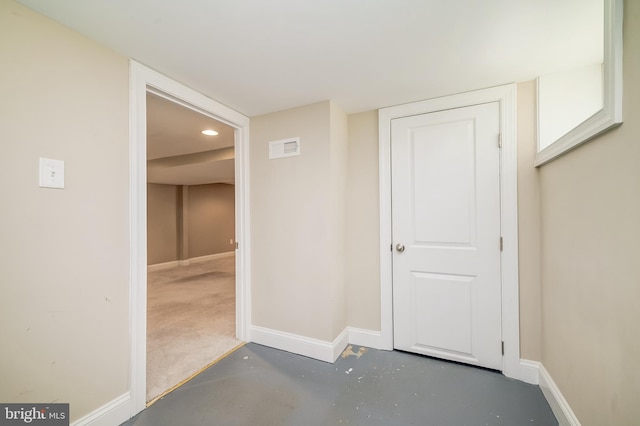 hallway featuring visible vents, baseboards, and concrete floors