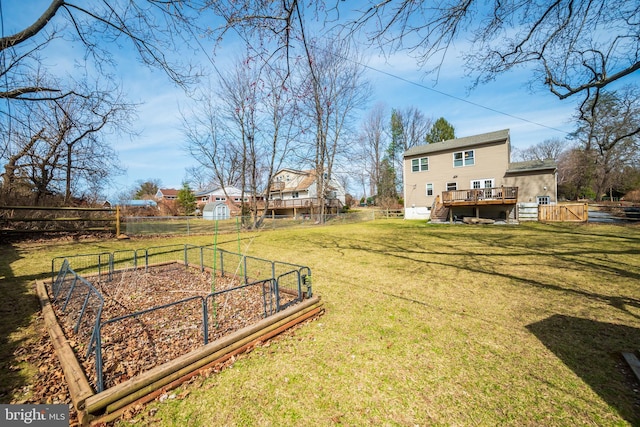 view of yard featuring a garden, a wooden deck, a fenced backyard, and stairs