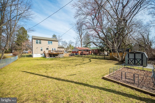 view of yard with a fenced backyard, a storage shed, an outdoor structure, a garden, and a wooden deck