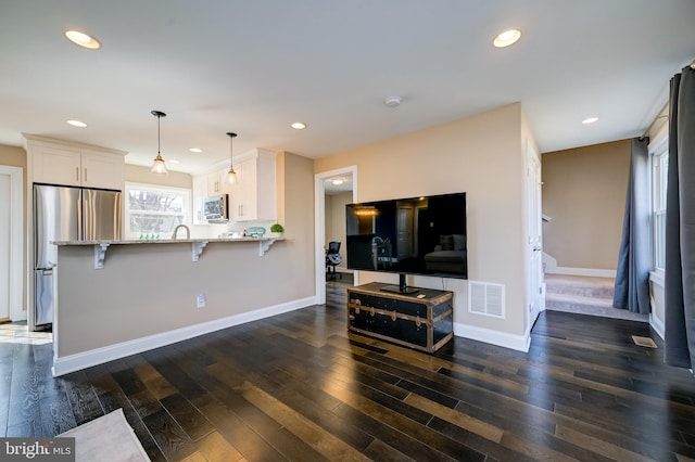 kitchen with light stone countertops, visible vents, dark wood finished floors, appliances with stainless steel finishes, and white cabinetry