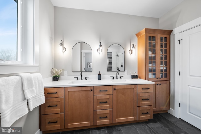 full bath with double vanity, walk in shower, and a sink