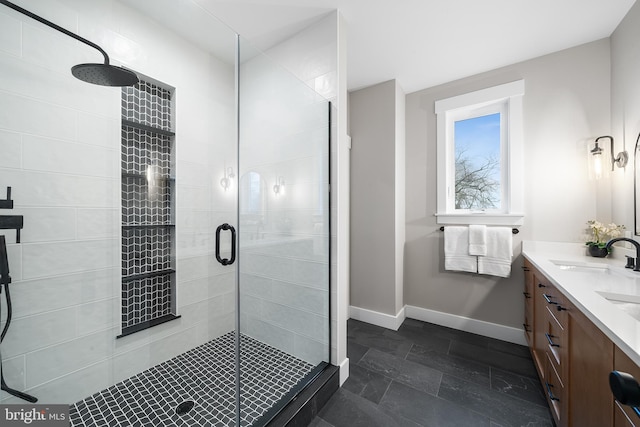 bathroom with a stall shower, vanity, and baseboards