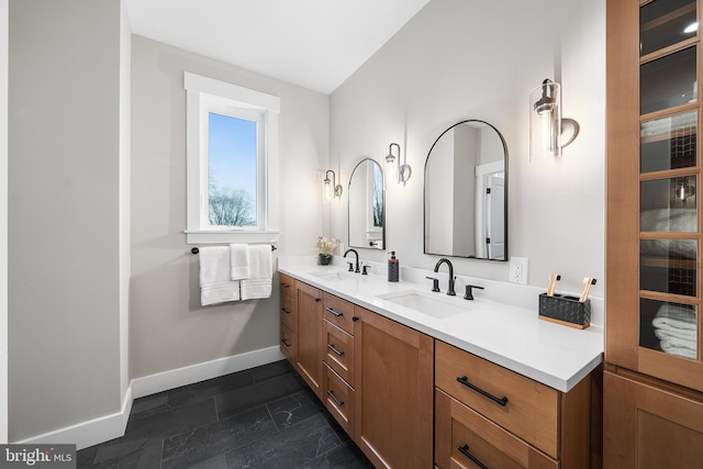 bathroom with a sink, baseboards, and double vanity