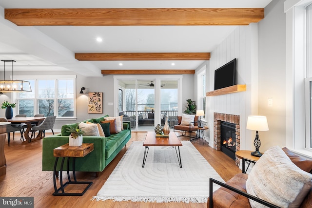 living room with a chandelier, a fireplace, wood finished floors, and beam ceiling