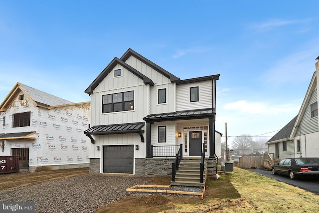 modern inspired farmhouse with covered porch, an attached garage, central AC unit, board and batten siding, and a standing seam roof