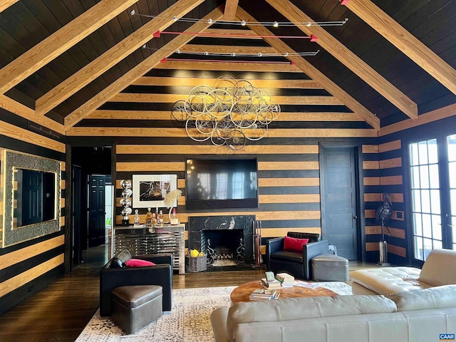 living area featuring lofted ceiling with beams, wooden ceiling, wood finished floors, an inviting chandelier, and a high end fireplace