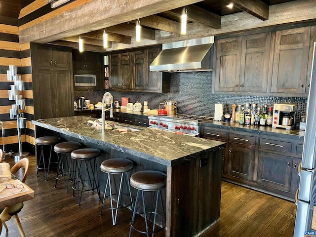 kitchen with tasteful backsplash, dark wood finished floors, stainless steel microwave, stove, and wall chimney range hood